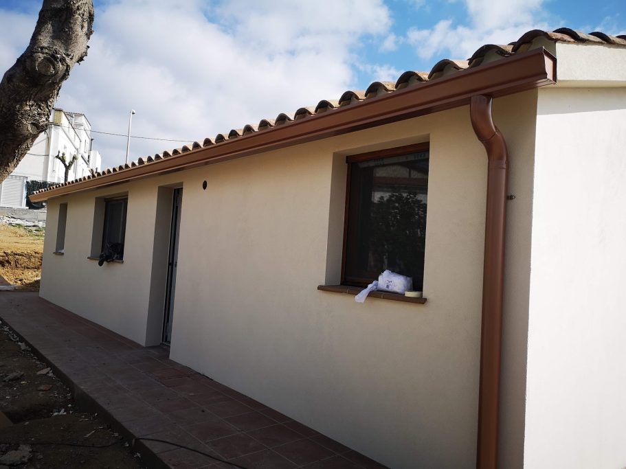 Casa de una planta con tejado a dos aguas y ventana, en un entorno rural.