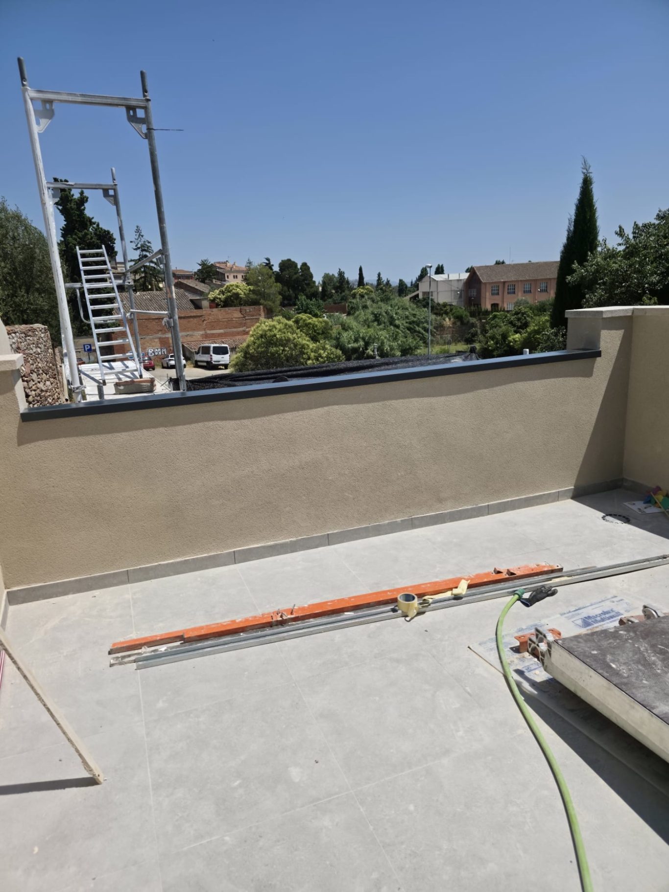 Terraza con vistas, equipo de construcción y una escalera en segundo plano.