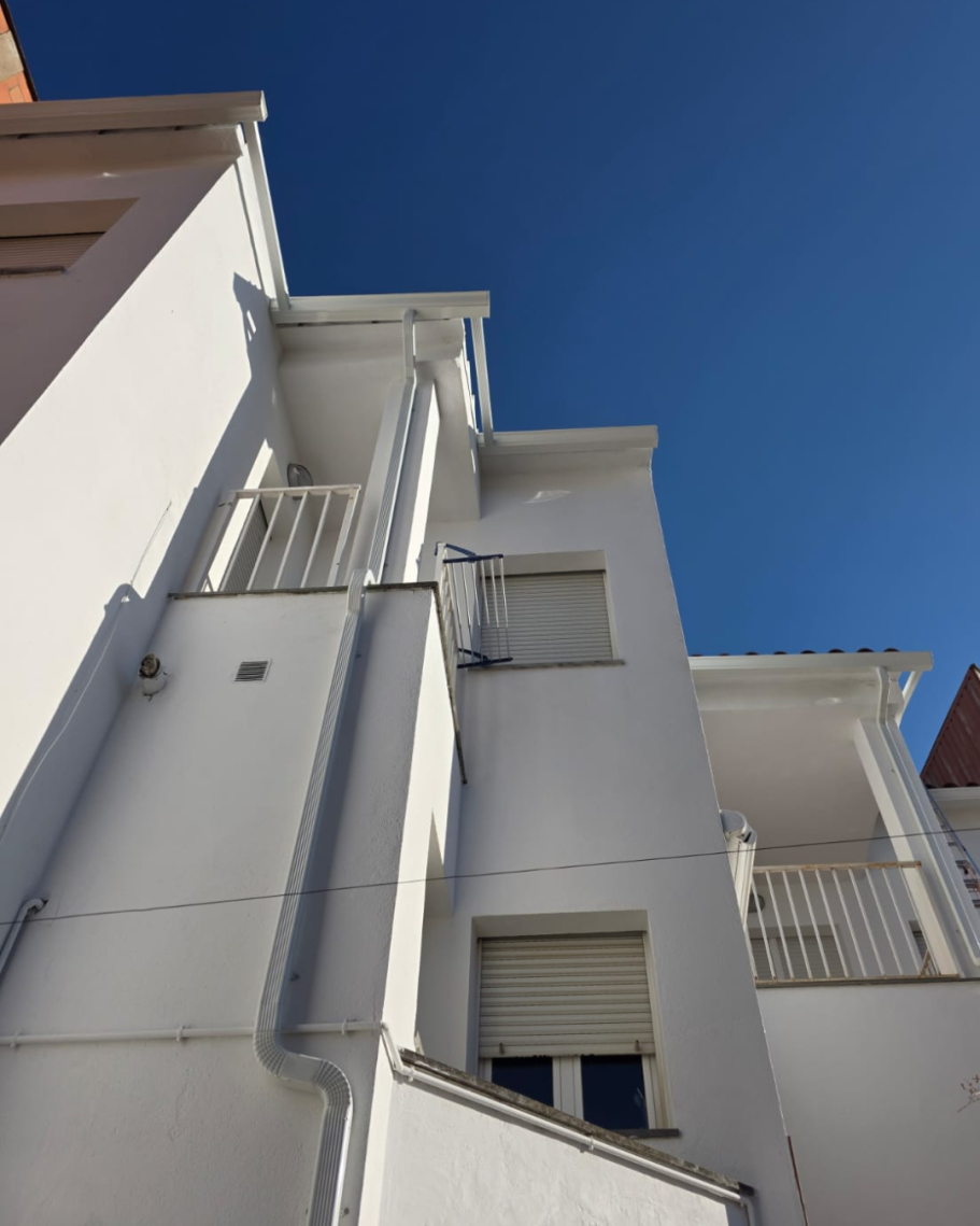 Fachada blanca de un edificio bajo un cielo azul despejado.