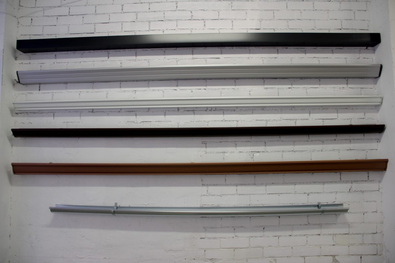 Seis listones de diferentes colores y materiales, dispuestos horizontalmente en la pared.