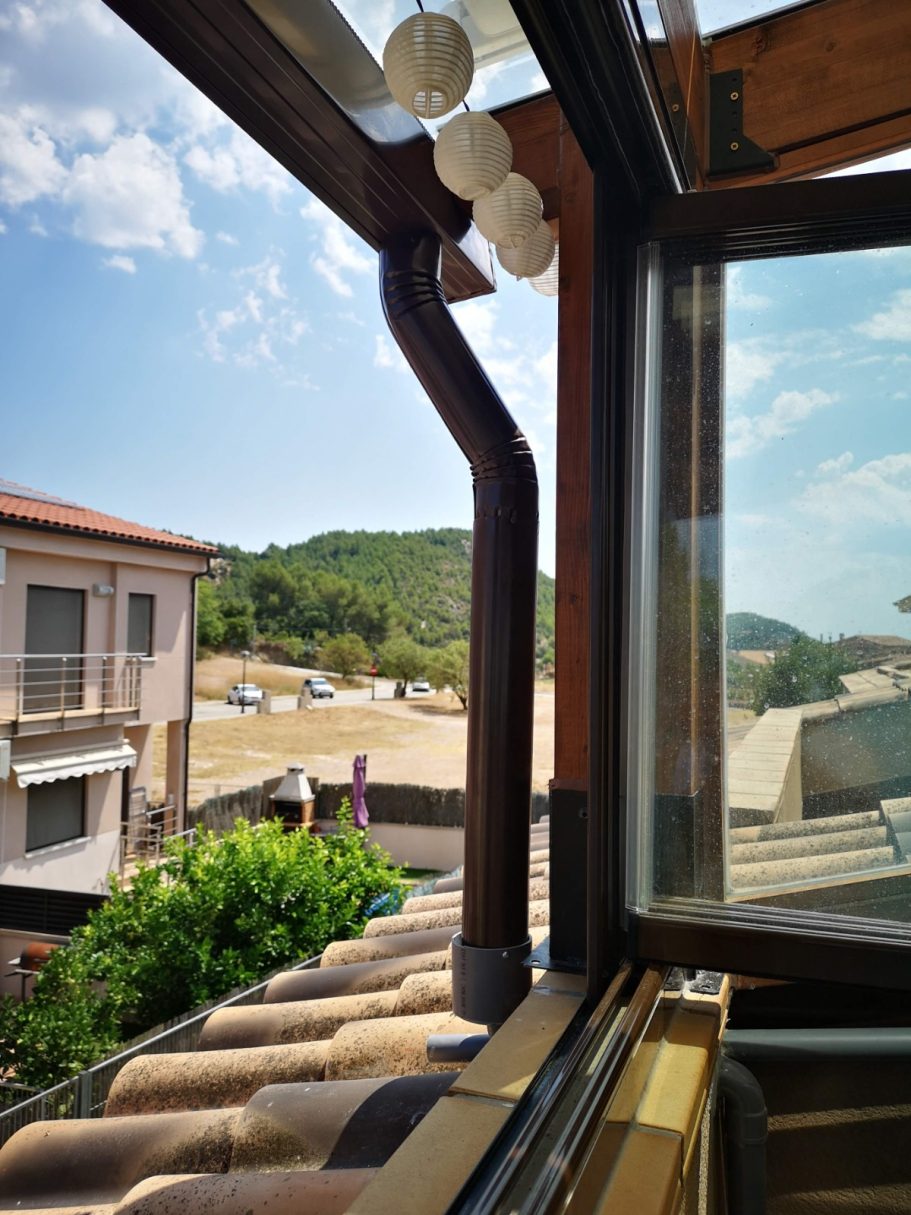 Terraza con canalon Vista desde una ventana que muestra un paisaje rural con casas y vegetación.