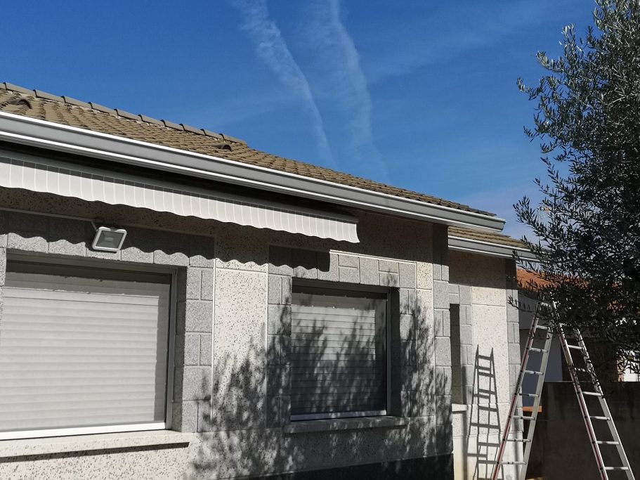 Fachada de una casa con un cielo despejado y una escalera al lado.