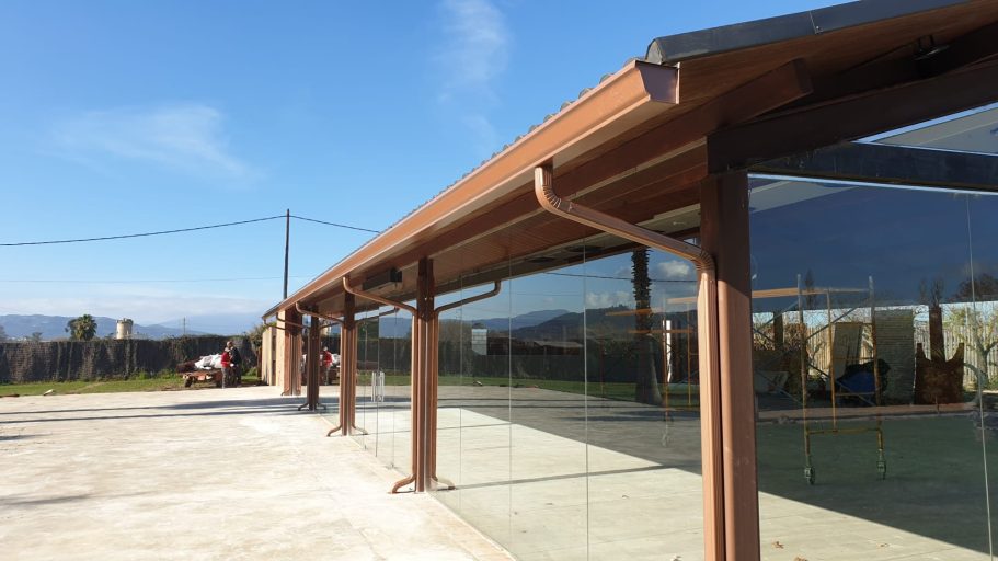 Estructura moderna con paneles de vidrio y techo alero, bajo un cielo despejado.